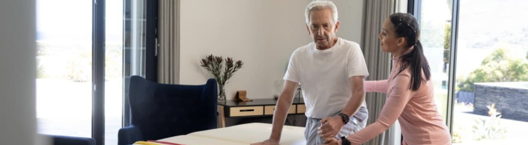 Older man doing exercises at home under allied health professional guidance